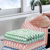 A stack of pink and green microfiber household cleaning cloths next to a kitchen faucet.