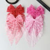 Three lace bows in shades of red, pink, and magenta displayed on a light surface.