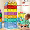 A young child is building a tower with colorful magnetic sheet tiles in various shades of yellow, orange, green, and blue.
