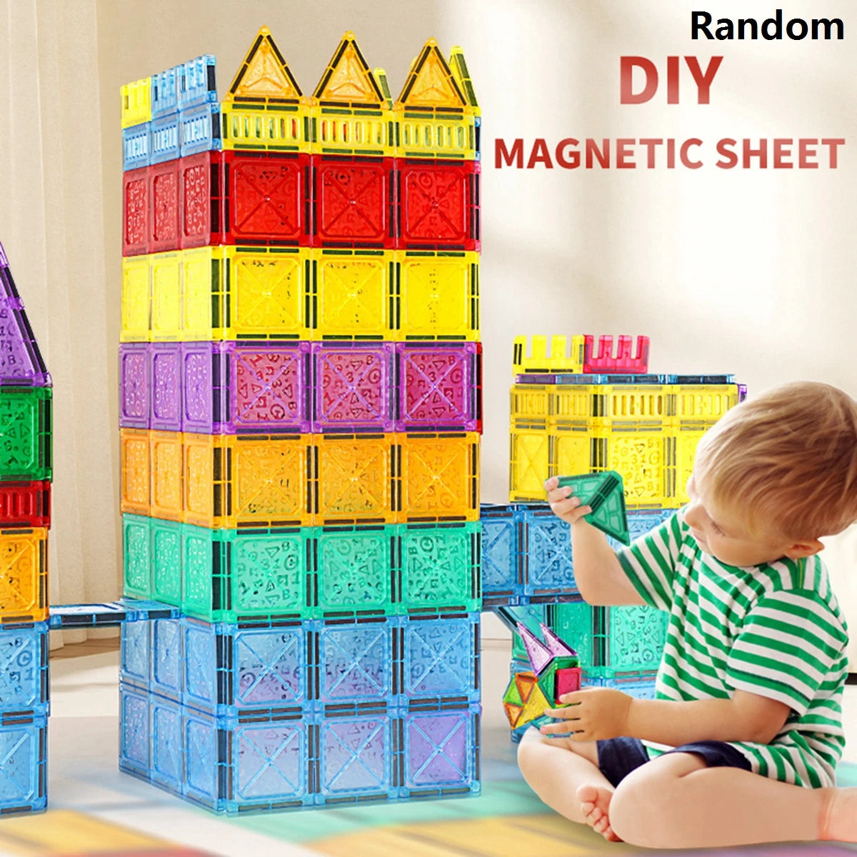 A young child is building a tower with colorful magnetic sheet tiles in various shades of yellow, orange, green, and blue.