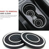 A set of two black and white non-slip silicone car cup holder coasters shown next to a product interior.