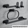 A five-piece black towel ring set with adhesive mounting hardware displayed against a gray wall.