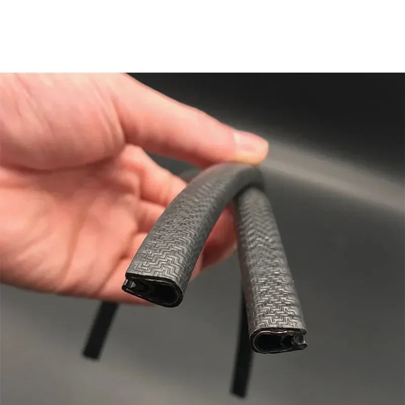 A hand holds a black U-shaped rubber edge trim with a metal core for automotive applications.