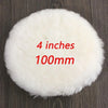 A white, fluffy wool polishing pad is shown on a dark wooden surface.