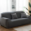 A modern gray elastic stretch sofa cover for a 3-seater sofa placed in a bright living room.
