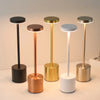 Five modern table lamps with varying finishes including black, copper, gold, and white bases and brass stems