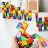 A hand holds a colorful, transformable fidget puzzle toy shaped like a horse, next to a row of colorful geometric blocks.