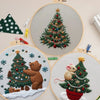 Christmas embroidery kit featuring a handcrafted set of knitted and embroidered Christmas trees and bears on a light backgrou