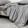 Luxuriöse graue Bambus-Decke über einem Bett, mit weichen Falten und glatteren Stoff.