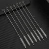 A set of thin stainless steel straws with looped ends arranged diagonally on a dark surface.
