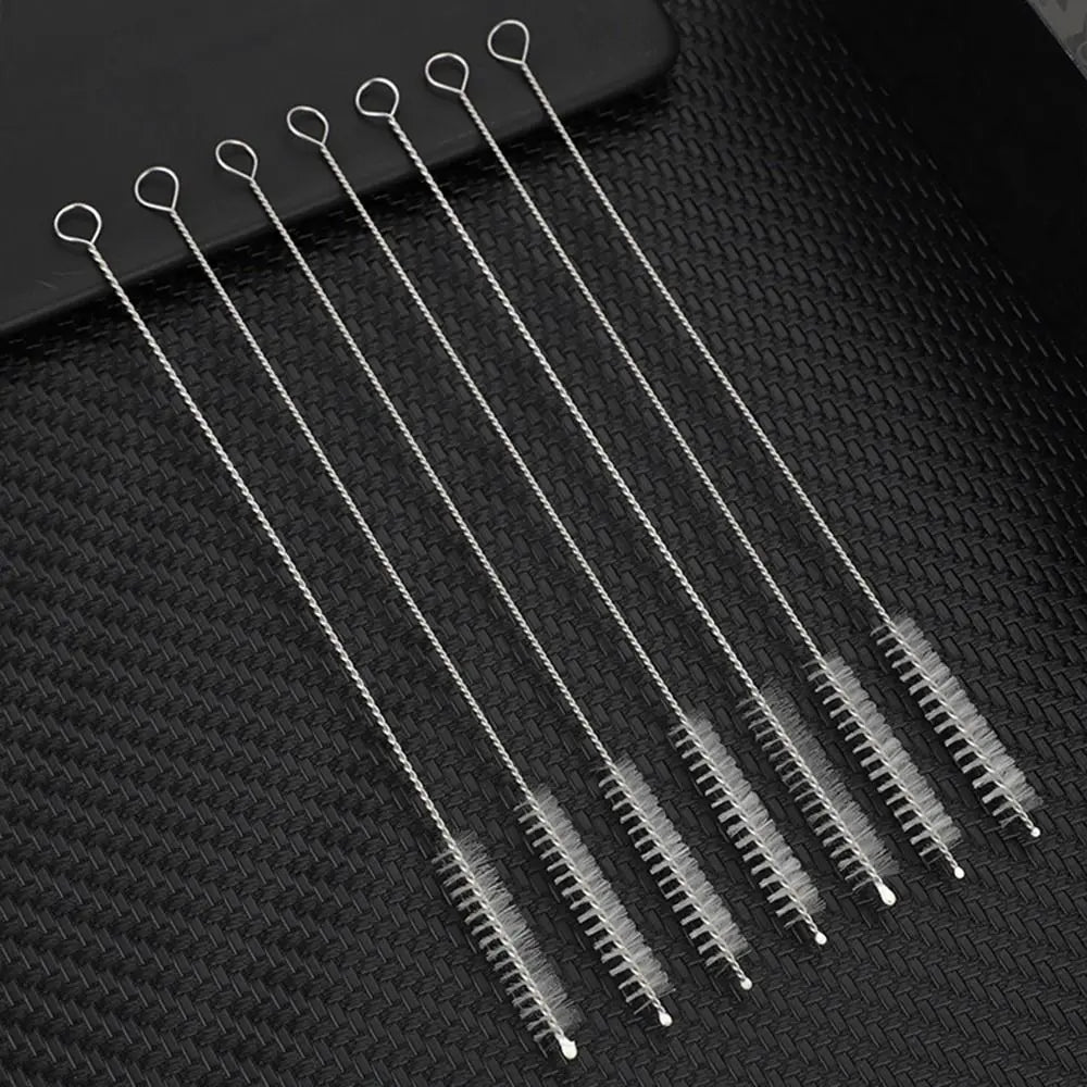 A set of thin stainless steel straws with looped ends arranged diagonally on a dark surface.