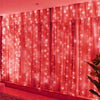 A row of sheer pink curtains illuminated by numerous warm LED fairy lights creating a glowing backdrop.
