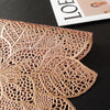 A close-up of a gold-toned, intricately cut floral pattern table runner or placemat.