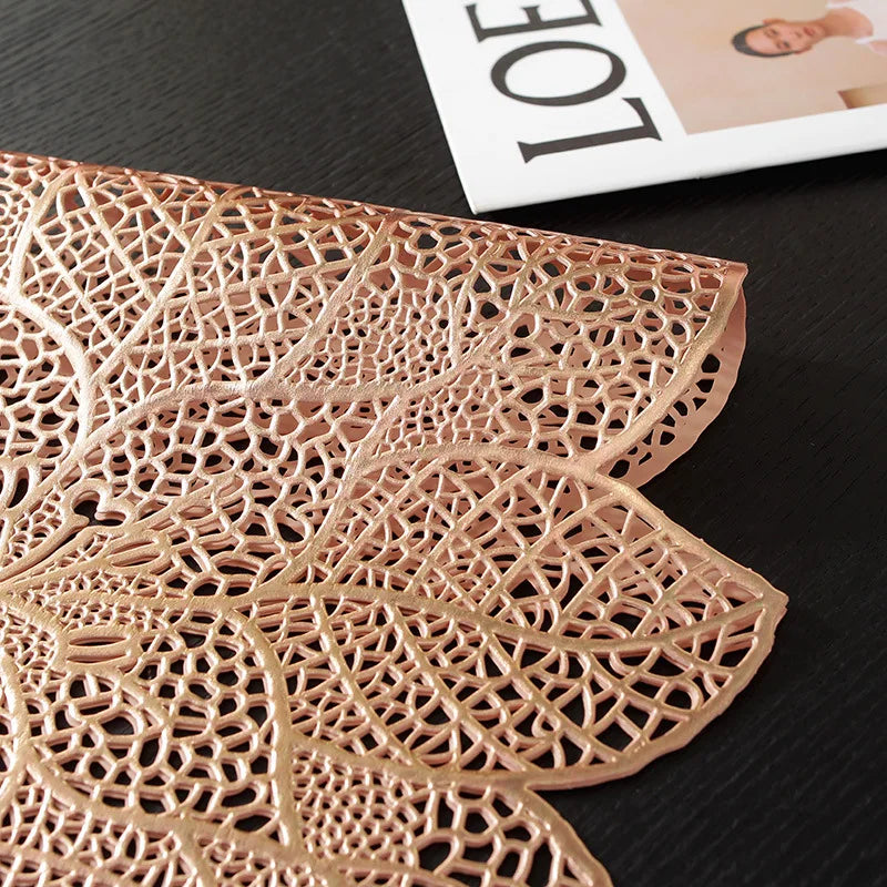 A close-up of a gold-toned, intricately cut floral pattern table runner or placemat.