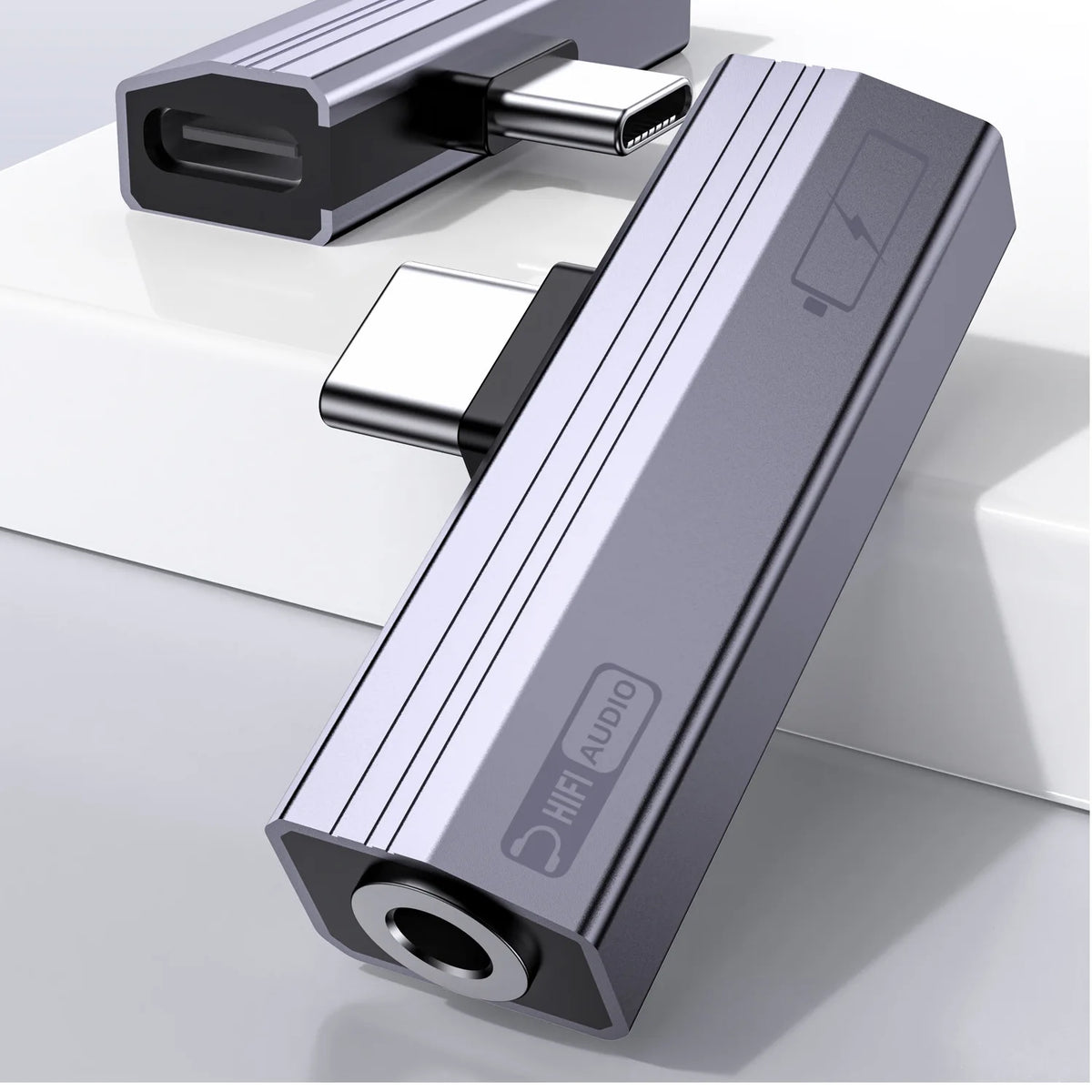A silver USB-C to 3.5mm audio adapter with charging support lying on a white surface.