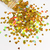 A pile of shiny holographic gold and iridescent heart-shaped sequins for resin crafts.