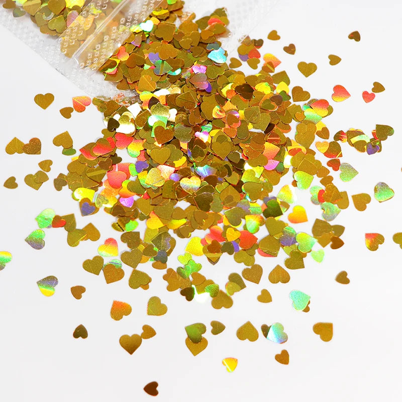 A pile of shiny holographic gold and iridescent heart-shaped sequins for resin crafts.