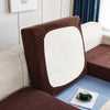 A close-up of a brown stretch jacquard sofa cover with a white cushion and blue accent fabric.