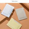 Three ultra-thin passport holders in light blue, beige, and pale yellow are displayed on a neutral background.