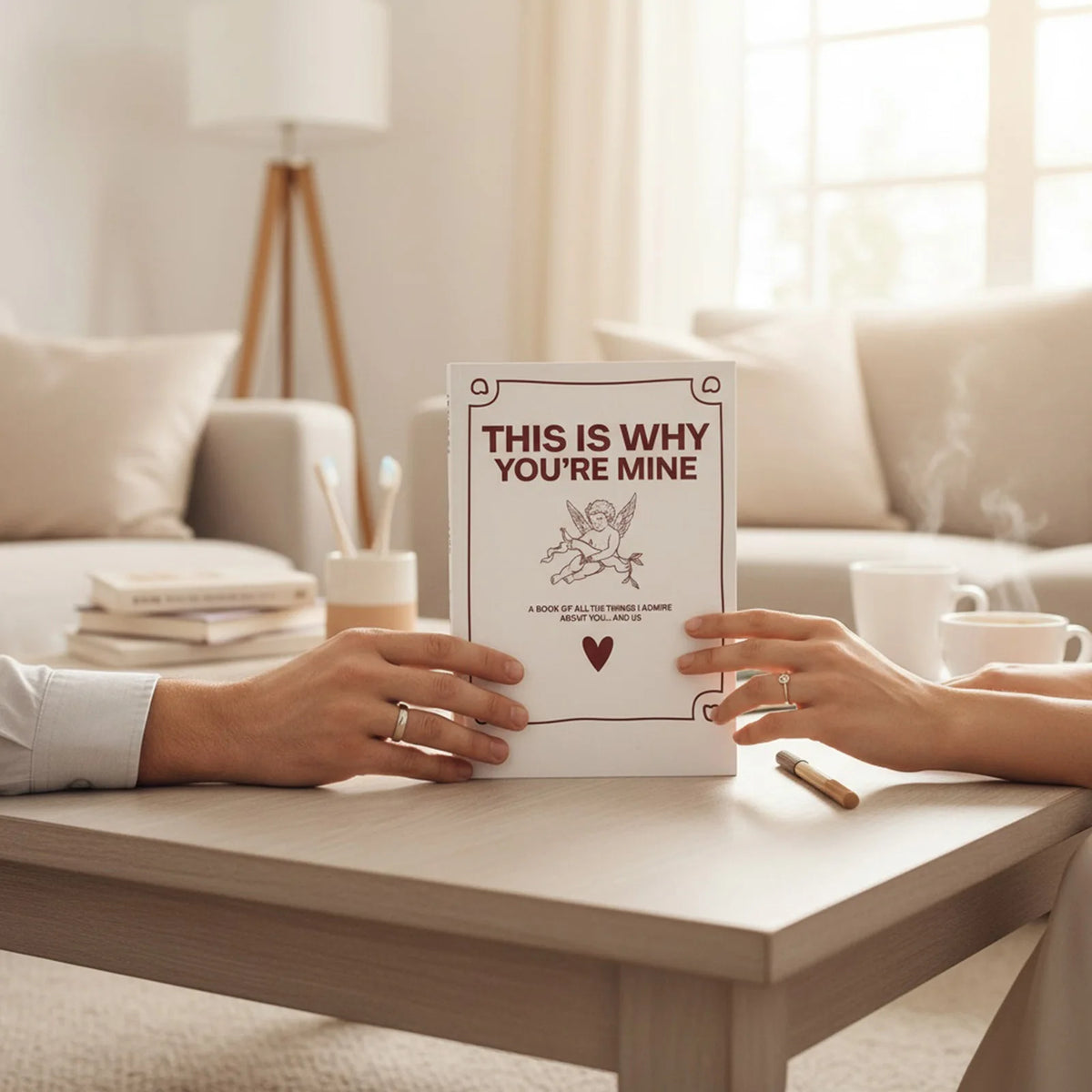 A pair of hands holds a personalized fill-in-the-blank love book for couples on a wooden table.