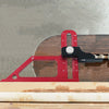 A red precision depth gauge with a black clamp is shown resting on a wooden surface.