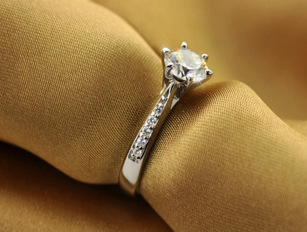 A close-up of a sterling silver ring featuring a clear tourmaline stone surrounded by zircon accents, worn on a finger agains
