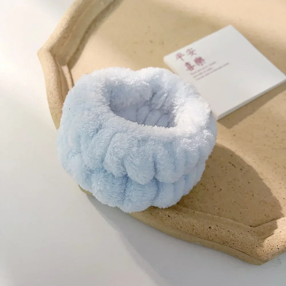 Light blue microfiber wrist sweatband and scrunchies for face washing resting on a beige tray.