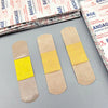 Three adhesive bandages are shown against a background of packaged medical supplies.