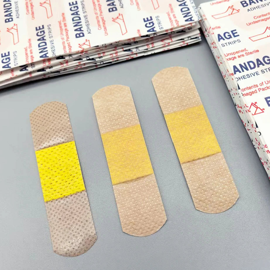 Three adhesive bandages are shown against a background of packaged medical supplies.
