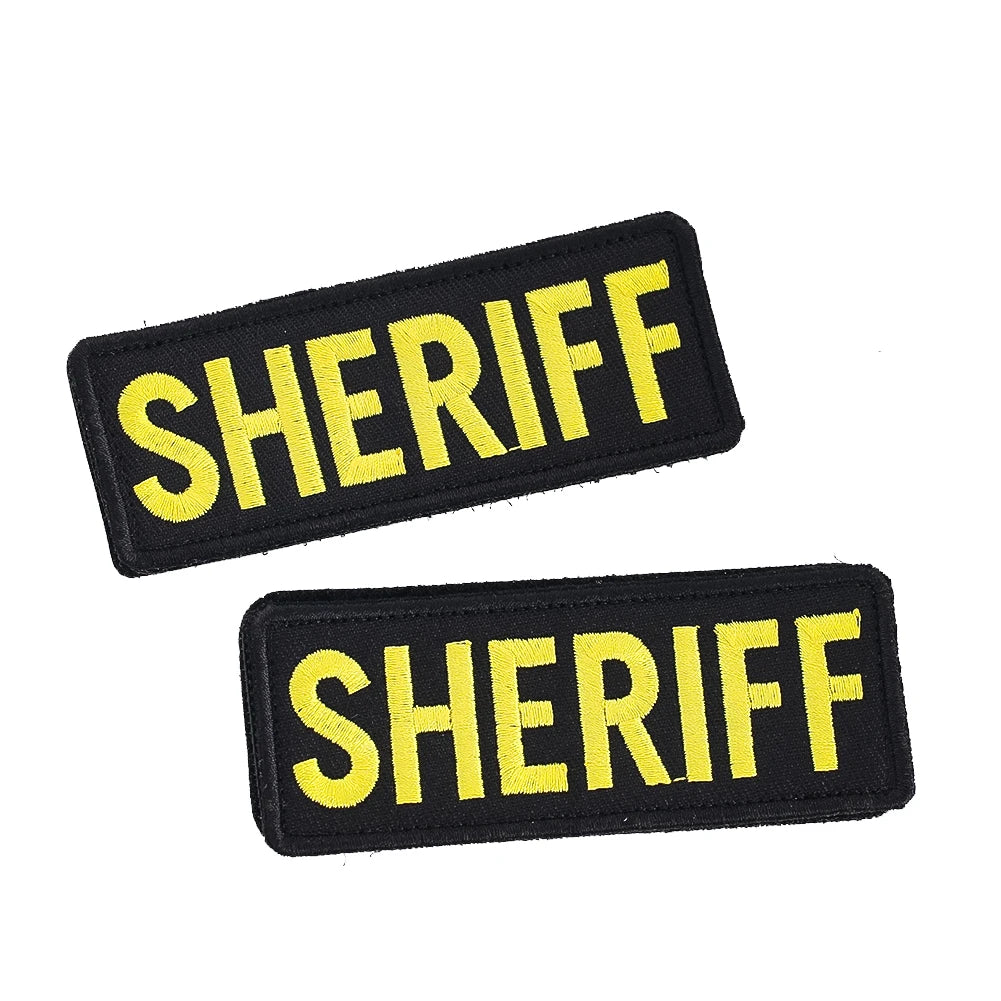 A pair of black sheriff patches with yellow lettering and hook and loop backing.