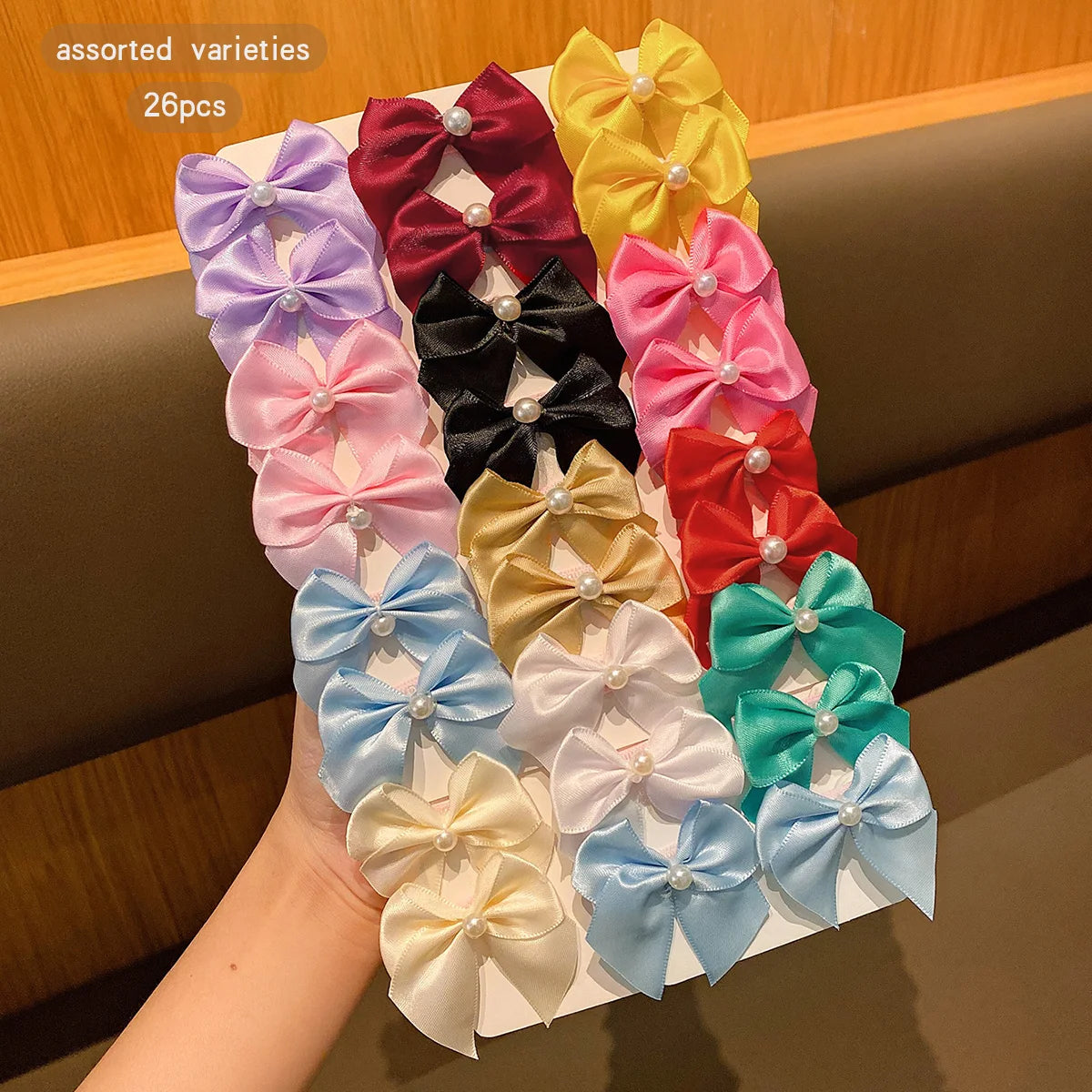 Assorted varieties of colorful fabric bows used as hair clips, displayed on a white surface.