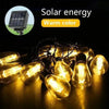 A close-up of warm color solar energy string lights illuminating a dark surface.