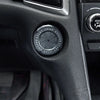 Close-up of a circular engine start stop button cover on a black car interior panel.