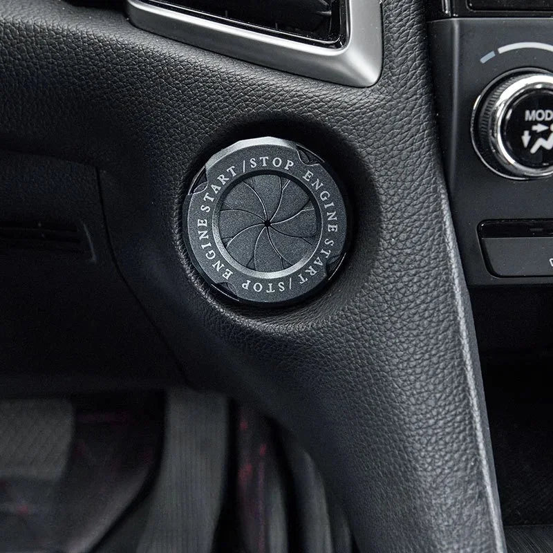 Close-up of a circular engine start stop button cover on a black car interior panel.