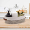 A woven cotton rope storage basket holding a roll of toilet paper and a small floral arrangement on a wooden surface.