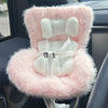 A pink and white faux fur miniature doll seat car vent decoration is shown inside a car interior.