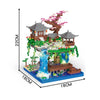 A miniature building block set depicting a traditional Japanese treehouse with a pagoda, lush greenery, and a flowing water f