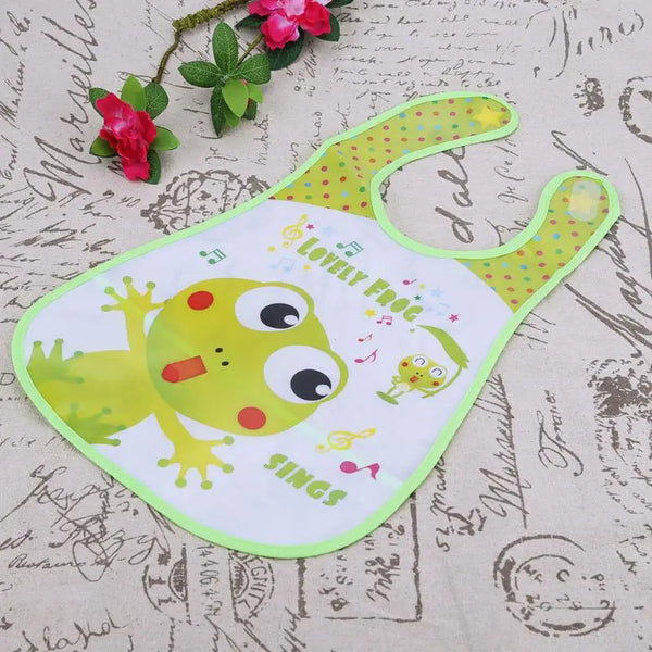 A white wipeable baby bib with a green border and a yellow frog design on the fabric