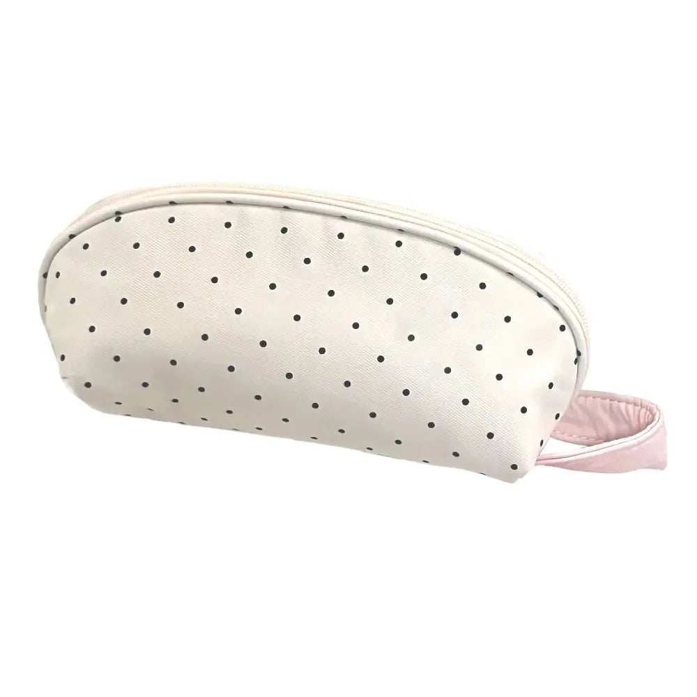 A shell-shaped pencil case in off-white fabric with small black polka dots and a pink strap.
