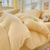 A beige cozy milk velvet bedding set featuring a duvet cover and pillows on a bed.