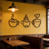 A set of three black iron art coffee cup wall decor pieces displayed on a yellow wall.