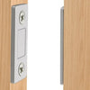 A close-up view of a silver magnetic door catch with two visible screws mounted on a light wood cabinet door frame.