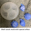 A white shell and starfish fondant mold set with a special glitter effect resting on a gray fuzzy surface.