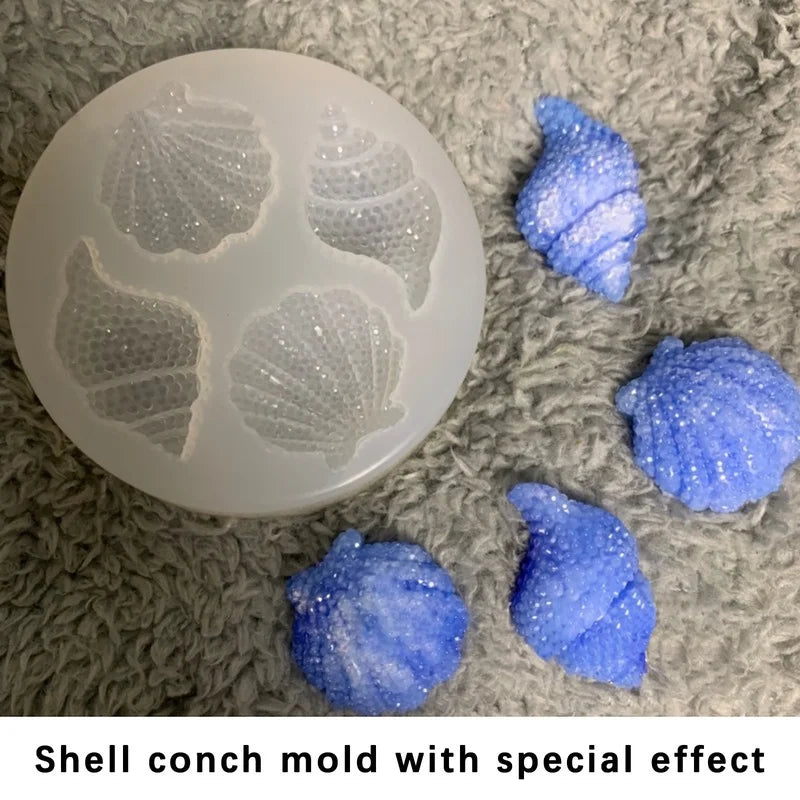 A white shell and starfish fondant mold set with a special glitter effect resting on a gray fuzzy surface.