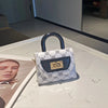 A small white and black patterned leather crossbody tote bag with a black handle resting on a white marble surface.