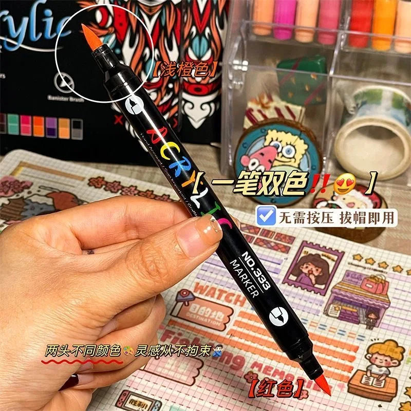 A hand holds a black dual-tip acrylic paint marker with a gold tip, demonstrating the product for art and craft.