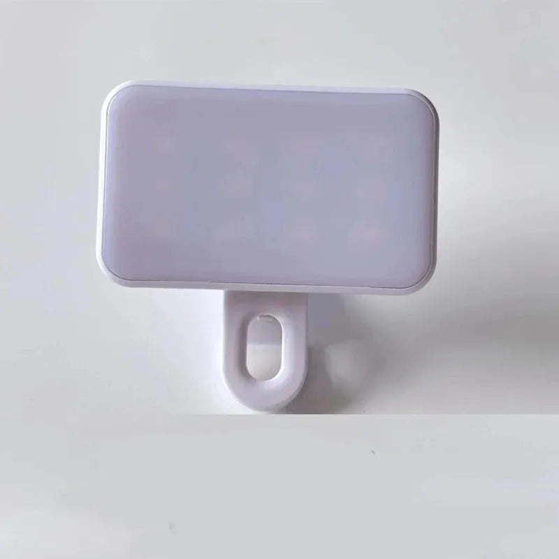 A white, rectangular clip-on LED selfie light with a loop for attachment.