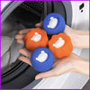 Hands are holding several blue and orange laundry balls with white foam on them inside a washing machine drum.