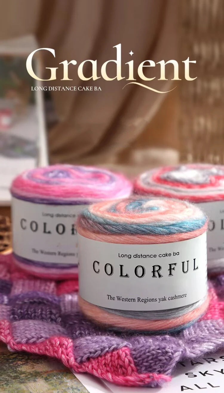 A spool of colorful Gradient cake yarn is displayed on a purple knitted fabric.