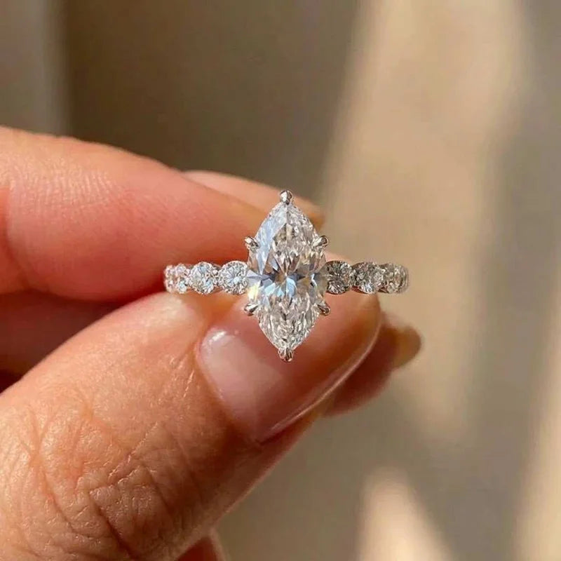 Une main tient une bague marquise en argent sterling zircon avec un centre de diamant brillant.